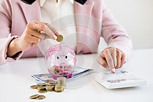 Close up of Businessman putting coin into small piggy bank , The