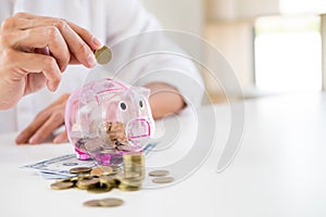 Close up of Businessman putting coin into small piggy bank , The