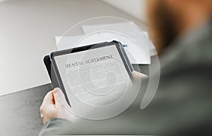 Close up businessman reading elecronic rental agreement on tablet.