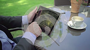 Close up on businessman`s hand browsing tablet. Outdoor. Steadicam shot.