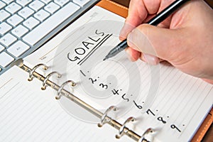 Close-up of a businessman`s hand writing goals and list in the diary
