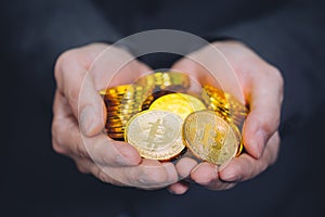 Close-up of businessman`s hands full of bitcoin sign of coins - cryptocurrency financial trade wealth and business investment