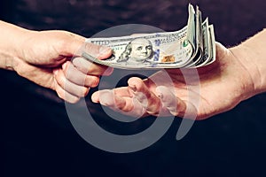 Close up of a businessman`s hands holding money over a black background