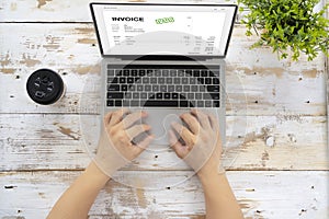 Close-up of businessman`s hands working on invoice on laptop at office