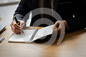Close-up of businessman's hands writing something down in a notebook