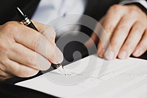 Close up of businessman signing a contract.