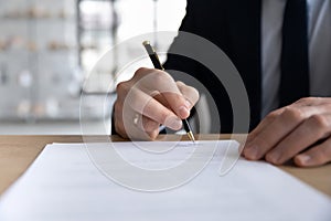 Close up businessman signing contract, holding pen, filling form