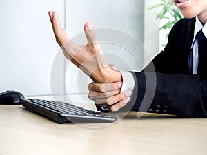 Young Asian businessman pain while using notebook computer in office