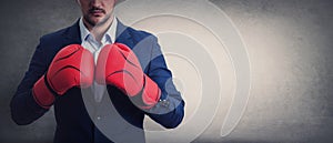 Close up businessman in suit with red boxing gloves stands ready in a fighting stance, punching his fists. Business person self