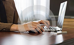 Close up businessman using laptop working in office with cell phone