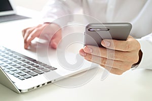 close up of businessman using mobile phone and laptop computer o