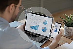 Close up businessman working with statistics on laptop and phone