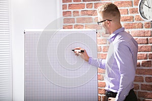 Businessman Writing On Grid Flip Chart