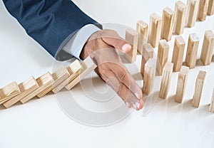 Close up of businessmans hand stopping the domino effect