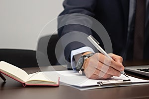 Close-up of businessmans hand using pen for notes