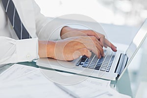 Close up on businessmans hands typing on his laptop