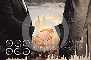 Close up of businessmen shaking hands with creative glowing business graph on blurry city background. Innovation, teamwork,