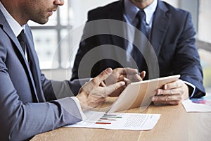 Close Up Of Businessmen Using Digital Tablet In Meeting