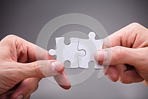 Close-up Of Businesspeople Holding Jigsaw Puzzle