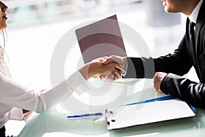 Close-up Of Businesspeople Shaking Hands At Office Desk after sign of contract