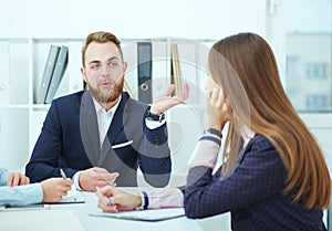 Close-up of businesspeople sitting at conference table communicating.