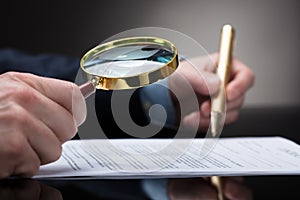 Businessperson Checking Contract Form Through Magnifying Glass