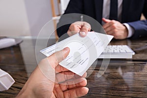Businessperson Giving Cheque To Colleague photo