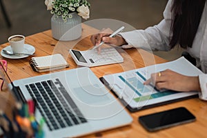 Close up Businesswoman or accountant using calculator and laptop for calaulating finance, tax, accounting, statistics