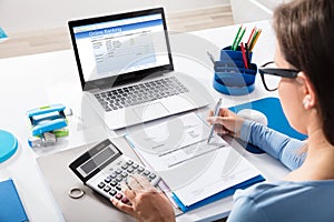 Businesswoman Calculating Invoice Using Calculator photo