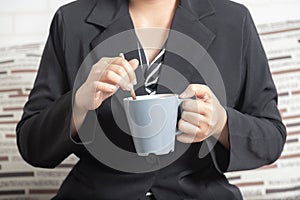 Close-up businesswoman hand holding a mug of coffee and stirring