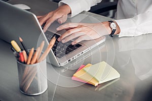 Close up businesswoman hand typing on laptop computer with note