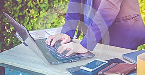 Close up businesswoman hand typing on laptop computer on table,working outside office with networking technology,tone filtered