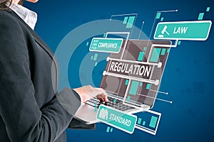 Close up of businesswoman hand using laptop with abstract digital regulation sketch or hologram on blue wall background. photo
