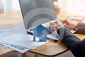 Close up of a businesswoman hands typing in a laptop in the office with paper house