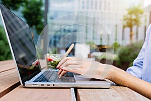 Close up of businesswoman hands typing on laptop sitting outside.