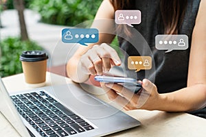 Close up businesswoman hands using mobile phone with group chat icon at outdoor nature park background.