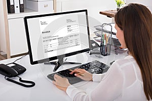 Businesswoman Looking At Invoice On Computer photo