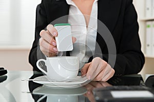 Close-up Of Businesswoman Putting Sugar In Cup