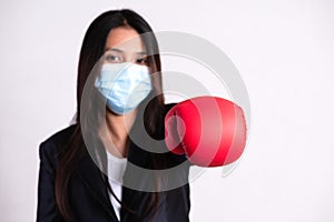 Close up of a businesswoman in a suit wearing red boxing gloves and Protective face mask, get ready for Coronavirus and pm 2.5