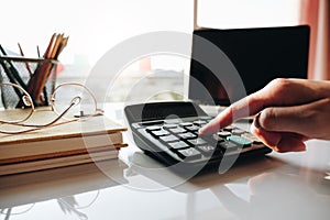 Close up Businesswoman using calculator and laptop for do math finance on wooden desk in office