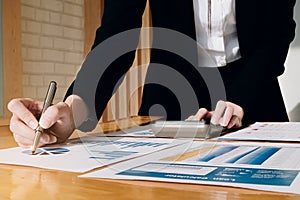 Close up Businesswoman using calculator and laptop for do math finance on wooden desk in office and business working background,