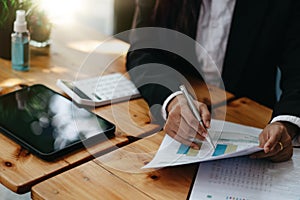 Close up businesswoman working on desk office using a calculator to calculate the numbers on chart report, finance