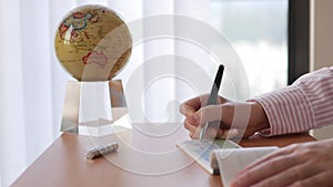 Close up of businesswoman writing a check with globe spinning inside the office
