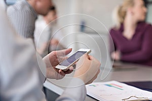 Close up of busineswoman hands using smart phone on meeting