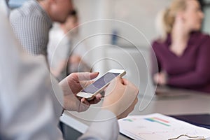 Close up of busineswoman hands using smart phone on meeting