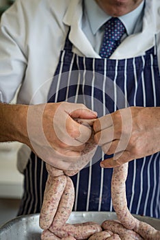 Close up of butchers hands linking sausages