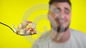 Close-up of caesar salad on forks. Out of focus in the background, a man really wants to eat Caesar salad with a fork