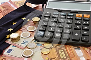 Close-up of a calculator, euro bills and diy facemask, designed as an European Union flag.