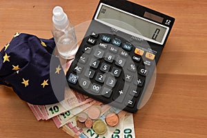 Close-up of a calculator, euro bills and diy facemask, designed as an Europian Union flag.