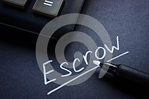 Close-up of a calculator and an inscription Escrow with a marker.